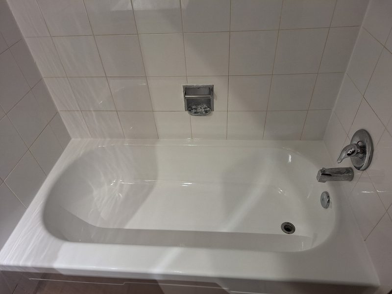 Refinished white alcove bathtub with white tile surround by Blackstone Tub Refinishers Calgary