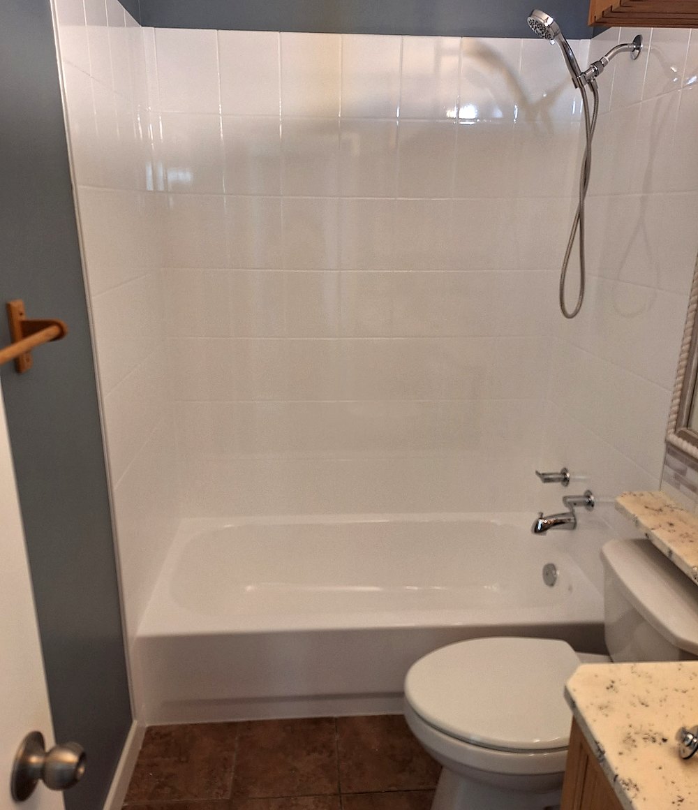 Refinished tub and tile surround by Blackstone Tub Refinishers Calgary — glossy white tile walls and bathtub